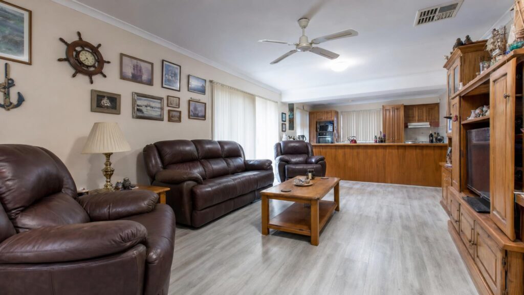 Outdated living room with vertical blinds, a matching brown leather lounge suite, honey oak furniture and nautical decor
